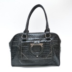 Bolsa  preta, modelo estruturado, com textura croco envernizada, de brilho intenso e aparência sofisticada. Possui alças duplas de mão. A frente apresenta aplique metálico decorativo em tom prateado, integrado ao design da aba. O interior é amplo e totalmente forrado em tecido personalizado com estampa da marca Geo Comp. 1 ziper com ausencia do acabamento para puxar. 52x36 cm