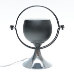 Orbit Lamp - Luminária  de estética futurista, de composição escultórica e equilíbrio geométrico. Corpo em metal de acabamento preto fosco, em formato semiesférico, suspenso por arcos metálicos concêntricos que evocam a ideia de órbita e movimento contínuo. Base em metal cromado de superfície espelhada. Fiação revisada e funcionando. 28x27 cm