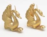 Par peças fundidas em bronze, representando aves estilizadas de longos pescoços recurvados e asas abertas em leque. Apresentam detalhamento nas penas e expressão altiva, típicas de elementos decorativos usados como acabamento ou adornos em móveis de maior requinte. 9x8x7 cm