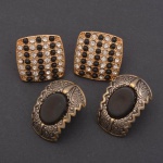 Par de brincos prateados com cabochão negro e par dourado com strass e pedrinhas pretas. 2,5x2 e 2x2 cm