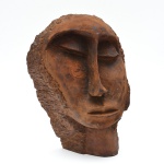 Louco (Boaventura da Silva Filho) - Escultura em madeira de forte caráter expressivo,obra com rosto de feições alongadas e assimétricas,  olhos semicerrados profundamente escavados, nariz proeminente e boca contida, transmitindo atmosfera introspectiva e silenciosa. A textura irregular do cabelo e das laterais da cabeça contrasta com o plano frontal do rosto, reforçando o jogo entre forma e expressão. Verso assinado com entalhe do artista Louco e as iniciais B.S. F. 40x30x17 cm