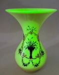 RARÍSSIMO VASO EM EM  OPALINA AMARELA  E  URALINA - FRANÇA (1890-1910) -Excepcional vaso em opalina amarela, enriquecido com uralina (vidro de urânio), cuja luminosidade especial se revela sob luz ultravioleta, irradiando o característico brilho verde fluorescente. A peça apresenta elegante forma em trombeta com bojo em pera, delicadamente ornamentada por esmaltes em azul cobalto e douração, emoldurando cartelas com motivos florais estilizados de grande refinamento decorativo. A  opalina amarela é reconhecida entre colecionadores e especialistas como uma das mais raras tonalidades produzidas pelas cristalleries francesas do final do século XIX e início do XX. Enquanto os exemplares em branco leitoso, azul ou rosa eram relativamente comuns, o amarelo  obtido com sais de urânio e apelidado de chrysoprase por Baccarat  foi produzido em quantidade bastante limitada, tornando-se altamente colecionável no mercado internacional. A sofisticação do esmalte pintado à mão aproxima esta peça das produções de Legras, Montjoye e PortieuxVallerysthal, ativos na França entre 1890 e 1910, época em que o vidro esmaltado florescia no contexto da Belle Époque e do Art Nouveau. - Peça de raridade destacada, testemunho do savoir-faire francês na arte do vidro, e um exemplar raro de opalina amarela com uralina, de grande interesse para colecionadores e museus especializados. Medidas: 23 cm de altura/ bocal 14,5 cm