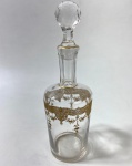BACCARAT- PEQUENA GARRAFA EM CRISTAL INCOLOR COM DECORAÇÃO DOURADA FRANÇA FINAL SÉC. XIX  INÍCIO SÉC. XX. CRISTAL gravado  a ouro com rico trabalho em guirlandas  e filetado em dourado E LAPIDADO COM DECORAÇÃO EM OURO APLICADO MANUALMENTE EM PADRÃO NEOCLÁSSICO DE GUIRLANDA E FESTÕES.TAMPA FACETADA ORIGINAL. ESTILO  NEOCLÁSSICO VITORIANO / BELLE ÉPOQUE. MEDIDAS: 21 CM