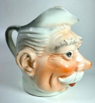 Antiga jarra escultórica em cerâmica com rosto masculino. Estilo Alemão Antigo- Jarra antiga em cerâmica esmaltada de tipologia incomum e grande presença estética, representando um rosto masculino maduro, com expressão marcada e volumetria escultórica. A peça remete á tradição germânica produzida entre o final do século XIX e início do século XX. Embora possui pequenos desgastes no esmalte na parte  da orelha e base, e pequeno fio de cabelo na parte interna, em nada compromete sua estabilidade e valor. Medidas: 20 cm de altura e 24 cm de largura.