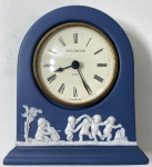 WEDGWOOD- RELÓGIO A PILHA  EM JASPER AZUL ESCURO  E BRANCO COM FIGURAS EM ALTO RELEVO COM MOTIVOS NEOCLÁSSICO MARCADO EM BAIXO RELEVO WEDGWOOD ENGLAND. POSSUI DEDICATÓRIA NA PARTE TRASEIRA. MEDIDAS: 12 CM . CURIOSIDADES: EM 1738 COMEÇARAM AS ESCAVAÇÕES DE POMPEIA E HERCULANO PRÓXIMO DE NÁPOLES NA ITÁLIA CRIANDO A PARTIR DESSA ÉPOCA, NA EUROPA, UM NOVO INTERESSE AO ESTILO NEOCLÁSSICO. EM 1759, JOSIAH WEDGWOOD FUNDOU UMA MANUFATORA DE PORCELANA INSPIRADA EM MOTIVOS DA ANTIGUIDADE CLÁSSICA, TORNANDO SUA EMPRESA CONSAGRADA MUNDIALMENTE. AS PEÇAS ERAM REALIZADAS COM UM TIPO DE MATERIAL AO QUAL FOI DADO O NOME DE JASPER.