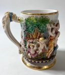CAPODIMONTE - ITALIA- CANECO EM PORCELANA CAPODIMONTE  COM DECORAÇÃO EM ALTO RELEVO EM ESTILO NEOCLÁSSICO, BORDAS EM OURO. MEDIDAS: 13 CM - CURIOSIDADES: A MANUFATURA CAPODIMONTE FOI FUNDADA EM 1743 PELO REI CARLOS DE BOURBON , NO PALÁCIO DE CAPODIMONTE EM NÁPOLES, SUAS CRIAÇÕES EM ESTILO ROCOCÓ, UTILIZAVAM A PASTA MOLE QUE É MAIS MALEÁVEL, DEIXANDO UMA TEXTURA MAIS AVELUDADA. SUA CARACTERÍSTICA É MARCADA COM n COROADO QUE REPRESENTA A PRIMEIRA LETRA DE NÁPOLES E A COROA POR SER UMA MANUFATURA REAL.