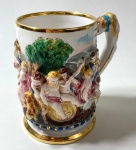 CAPODIMONTE - ITALIA- CANECO EM PORCELANA CAPODIMONTE  COM DECORAÇÃO EM ALTO RELEVO EM ESTILO NEOCLÁSSICO, BORDAS EM OURO. MEDIDAS: 13 CM - CURIOSIDADES: A MANUFATURA CAPODIMONTE FOI FUNDADA EM 1743 PELO REI CARLOS DE BOURBON , NO PALÁCIO DE CAPODIMONTE EM NÁPOLES, SUAS CRIAÇÕES EM ESTILO ROCOCÓ, UTILIZAVAM A PASTA MOLE QUE É MAIS MALEÁVEL, DEIXANDO UMA TEXTURA MAIS AVELUDADA. SUA CARACTERÍSTICA É MARCADA COM n COROADO QUE REPRESENTA A PRIMEIRA LETRA DE NÁPOLES E A COROA POR SER UMA MANUFATURA REAL.