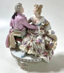 GRUPO EM PORCELANA DE SAXE, REPRESENTANDO CASAL DE NAMORADOS EM UMA NAMORADEIRA -ALEMANHÃ SÉC XIX - MEDIDAS: 15 X 15 CM