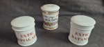 Três potes de farmacia em porcelana marcados Extrato de Ratania e Digital Alcoh medindo 9 cm de altura por 8 cm de diâmatro, e Belladona Par medindo 8 cm de altura por 7 cm de diâmatro.