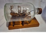 Antiga montagem de caravela no interior de garrafa de Chivas medindo 17 cm por  cm de diâmetro.