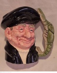 Antiga caneca de coleção em porcelana Inglesa policromada em forma de Marinheiro com pega representando crustaceo, medindo 19 cm de altura por 18 cm por 13 cm, apresenta faltas na pintura preta necessitando retoques.