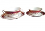 Luxuoso conjunto de 4 peças porcelana Steatita, sendo 1 xícara de chá, 2 pires e 1 consomé em tom vinho e branco decoradas ricamente com arabescos filetados a ouro. Marcas do tempo. -dim- Xícara 9,5x5,5 / consomé 11,5 x 5,5 cm
