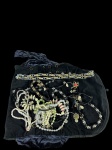 Lote diversificado de bijuterias e joias de fantasia, incluindo colares e pulseiras em vários materiais e estilos, acompanhado de seu mostruário/porta-joias de veludo preto. Marcas do tempo.