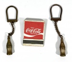 Lote com 3 itens colecionáveis da Coca-Cola sendo 2 chaveiros em formato de garrafa produzidos em metal na cor Bronze e uma caixa de fósforos da marca produzidos pela American Match Co. NY