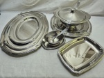 Baixela com 8 peças em aço inox Tramontina com borda recortada. Composto de sopeira com concha, molheira com concha, 2 travessas redondas rasas, 3 travessas ovais rasas e 1 travessa retangular.