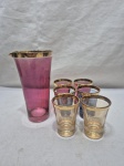Jarra, coqueteleira com 6 copinhos em demicristal colorido com friso ouro. Medindo a jarra 8cm x 15,5cm de altura; copo 5cm x 7cm de altura. Com leve desgaste na douração.