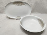 Jogo de 2 travessas, sendo uma oval e uma redonda em porcelana Schmidt com pintura de folhas. Medindo a oval 32cm x 21cm.