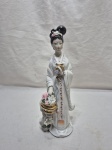 Linda escultura de gueixa em porcelana. Medindo 29cm de altura. Necessita de reparos na alça da cesta.