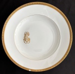 LOUÇA DO IMPÉRIO - Prato fundo em pasta de porcelana francesa LIMOGES adornado com friso em vibrante ouro e monograma do arquiteto, pintor e capitão JOAQUIM CÂNDIDO GUILHOBEL (Lisboa, 1787 - Rio de Janeiro, 1859). Louça da aristocracia do Império Brasileiro. Possui discreto bicado. Mede 25cm.