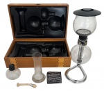 Cafeteira "lobinho" ou sifão, sem uso, acondicionada em caixa original de madeira. Acompanha manual. Mede 38 x 23cm.
