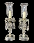 Par de elegantes luminárias de mesa em cristal lapidado, com cúpulas gravadas e pingentes facetados em diferentes formatos.Peças de fino trabalho artesanal, em estilo clássico, evocando o requinte dos interiores europeus do século XIX. Ideais para ambientações refinadas ou coleções de cristal decorativo. Mede 41 cm altura.