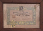Antigo diploma histórico da Exposição Industrial do Centenário da Fundação de Petrópolis (1943), concedido à Companhia Metropolitana, acompanhado do anúncio original da Fábrica de Fiação e Tecidos de Cascatinha. Peça rara, moldurada com madeira nobre, com medalhão e decoração original  testemunho autêntico da indústria têxtil petropolitana do início do século XX. Protecao de vidro e placa de madeira no verso. Medida total 47 x 64 cm.