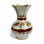 EUROPA - Gracioso vaso em porcelana europeia esmaltada, fartamente decorado com guirlandas de flores multicoloridas, faixas rubi e detalhes em ouro, finalização iridescente no bojo superior. Peça delicada e ornamental, típica da produção europeia de inicio do século XX. Mede 16 cm altura.