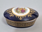 LIMOGES - Caixa porta joias oval em porcelana azul cobalto, decorada com arabescos dourados e cena romântica na reserva central. Med. 11 x 08 x 05 cm