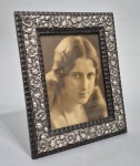 Antigo porta retrato madeira com frisos em Prata, cinzelada com delicadas flores. Possivelmente português. Contarste não localizado. Med. 25 x 20 cm.
