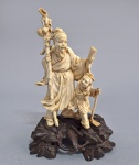 CHINA, DINASTIA QING, Séc.XIX - Antiga e bem executada escultura chinesa em Marfim, representando Ancião e criança. Base em madeira esculpida original. Com ideograma Tian e numero de inventário na base. Medida total: 20 cm.
