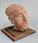 Cabeça de princesa egípcia, no estilo Amarna, com sua cabeça característica oval e longilínea. Reprodução de Museu. Material não identificado. Med. 18 x 18 x 18 cm.