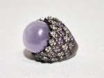 Anel em prata 925 com cabuchon central de Selenita púrpura e cravejado no entorno com Zircônias roxas e brancas. Aro: 18