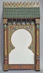 Espelho marroquino em madeira no formato de janela árabe, esculpido e pintado a mão com flores e arabescos. Assinado e localizado no verso. Anos 70/80. Parte superior, no formato de telhado. Detalhes em douração. Med. 75 x 38 x 6.5 cm. EX-COLEÇÃO SCARLET MOON DE CHEVALIER.