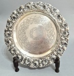Antiga salva em metal folheado a Prata, fundo e boda cinzelados e decorados com botões de Rosas e folhagens. Pés em garra. Sem marca visível. Med. 31 x 04 cm