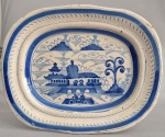 Antiga travessa em faiança azul e branca, no estilo chinês, decorada com pagodes e paisagens. Sem marca. Séc.XIX. Possui restauro na borda. Med. 38 x 30 cm