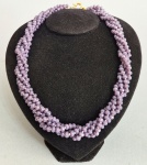 Colar torcido em belíssimas pedras possivelmente Kunzitas na cor púrpura. Alto brilho. Fecho boia dourado. Med. 55 cm.