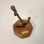 Escultura decorativa em formato de âncora fixada sobre base de madeira. A peça apresenta plaqueta com a inscrição Marina DItalia -São Paulo- Sta. Bárbara 1999, possivelmente tendo produção comemorativa ligada a evento ou representação marítima italiana no Brasil. Acabamento com pátina natural do Bronze e linhas clássicas da simbologia naval, conferindo caráter histórico discreto e boa presença estética.                                                                         Estado de conservação: bom estado geral, com leves marcas do tempo compatíveis com a idade. Medindo: 15x11x11