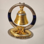 Elegante sino de mesa com temática naval, produzido em metal com acabamento dourado e estrutura circular moderna. A base apresenta o emblema com estrela vermelha e âncora, além da inscrição em chinês , que traduzido significa Marinha do Exército de Libertação Popular da China.  Medindo: 14x13x7