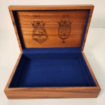 Caixa comemorativa da Força de Submarinos da Marinha do Brasil, produzida em homenagem ao centenário da corporação (19142014). Confeccionada em madeira, possui acabamento elegante e interior revestido em veludo azul, tampa apresenta uma arte detalhada com submarinos em navegação e o brasão da Marinha do Brasil com âncora. Na parte interna, há gravações dos anos comemorativos e o emblema da Força de Submarinos, reforçando o caráter histórico e institucional da peça. Medindo: 8x30x20