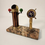 Conjunto decorativo de inspiração náutica composto por bússola protegida por cúpula metálica e telégrafo marítimo ornamental com inscrições como Stop, Astern e Ahead, além da marcação London no mostrador. Produzido em metal com pátina natural e apoiado sobre base de granito, é uma peça elegante e pesada, ideal para escritórios, estantes ou coleções temáticas. Medindo: 18x20x10