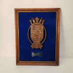 Peça decorativa composta por um brasão marítimo ricamente entalhado em madeira, exibindo elementos clássicos como âncoras, cordas, embarcações e globo central, símbolos tradicionalmente ligados à navegação e à autoridade naval. Medindo: 38x30