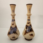 Elegante par de vasos atribuídos à Poschinger Krystallie (PK), tradicional manufatura alemã conhecida pela qualidade e acabamento refinado de suas peças. Produzidos em vidro de tom marfim acetinado, apresentam delicada decoração floral em azul com detalhes naturais em tons amarronzados, criando um visual clássico e muito sofisticado. Medindo: 31x12
