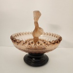 Elegante centro de mesa em vidro fosco de tonalidade âmbar, atribuído à manufatura de Joseph Inwald, tradicional na produção de vidros decorativos europeus. A peça possui borda com acabamento em esferas, corpo com suaves relevos e uma escultura feminina central que traz movimento e personalidade ao conjunto. Medindo: 33x30