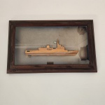 Maquete artesanal representando o submarino U-27, cuidadosamente esculpida em madeira e protegida por moldura com vidro frontal. A peça apresenta bons detalhes estruturais, incluindo torre, convés e pequena bandeira brasileira. Medindo: 56x34