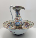 - Cia das Índias- raro e imponente conjunto de jarro e bacia em porcelana chinesa, ricamente ornamentado na paleta Famille Rose, típica do período tardio da dinastia Qing. A decoração apresenta amplas reservas figurativas com cenas cortesãs, ambientes palacianos e personagens finamente delineados, intercaladas por bordas com florões, arabescos e elementos tradicionais da estética cantonês. O jarro, de corpo faceteado e bocal ondulado, exibe narrativa contínua em esmaltes de ótima vivacidade e saturação. A bacia, de largo diâmetro, repete o mesmo programa iconográfico, formando um conjunto altamente decorativo e de grande presença visual. As bases apresentam sinais coerentes de idade, com desgaste autêntico do esmalte, reforçando a antiguidade da peça. 50 x 55 centímetros.