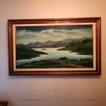 Alberto Matera (19392016), óleo sobre tela, intitulado Contemplando o Infinito, datado de 1987. Paisagem serena e profundamente atmosférica do artista brasileiro Alberto Matera, reconhecido por suas composições bucólicas de montanhas, lagos e horizontes amplos. Nesta obra, intitulada Contemplando o Infinito, Matera apresenta um panorama de montanhas azuladas ao fundo, com espelho dágua sinuoso e áreas de vegetação verde intensa, acompanhadas de pequenas figuras humanas que reforçam a escala monumental da natureza. Dimensões:0,80x1,20