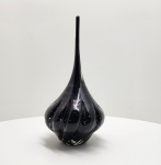 Escultura em vidro artístico de Murano Itália, século XX. Elegante escultura em vidro de Murano, de corpo sinuoso e alongado, executada em vidro negro translúcido com inclusão de bolhas regulares e delicado efeito espiralado. O trabalho revela a maestria dos mestres vidreiros de Murano, que, por meio do sopro livre e modelagem a quente, obtêm formas fluidas e equilíbrio entre peso, transparência e movimento. O design contemporâneo e a pureza da execução refletem a tradição artesanal veneziana reinterpretada ao longo do século XX. Dimensões aproximadas: 40 x 20 centímetros.