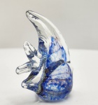 Elegante escultura de peixe em vidro artístico Murano, modelado à mão em massa vítrea translúcida com inclusões marmorizadas em azul profundo, branco e nuances violáceas. A peça apresenta corpo arredondado de grande movimento visual, barbatanas altas em vidro cristalino e base totalmente lisa, típica do acabamento manual veneziano. A transparência envolve delicadas bolhas aprisionadas e veios ondulados que conferem efeito aquático natural e sofisticado. Trabalho de bancada, executado em técnica sommerso com mesclas internas, oferecendo excelente presença decorativa. Dimensões: 10x9x5 centímetros.