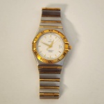 Relógio Omega Constellation Perpetual Calendar, modelo suíço clássico conhecido pela precisão e acabamento refinado. Possui caixa em aço inoxidável combinada com detalhes em ouro, incluindo bezel com algarismos romanos, coroa e elementos do bracelete, criando contraste sofisticado e valorizado no mercado. Mostrador claro texturizado com marcadores aplicados e calendário na posição das 3 horas. Fundo com o tradicional medalhão do observatório, símbolo da linha Constellation e de sua excelência cronométrica.                                                                                                         Bracelete original integrado em aço e ouro, com fecho assinado pela marca.