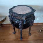 Mesa oriental entalhada, início a meados do século XX, executada em madeira maciça com rica talha floral em toda a estrutura. O tampo octogonal em mármore rosa contrasta elegantemente com o entalhe profundo, composto por flores de ameixeira, volutas e frisos de contas. As pernas, igualmente trabalhadas, apresentam motivos vegetais e terminações em garras estilizadas. Peça de elaboração artesanal, típica da produção sino-indonésia.Dimensões:81x57x57 centímetros.